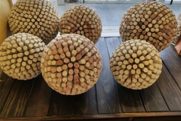 Chaveiro artesanal feito com uma rolha de vinho e pequenos acessórios coloridos, mostrando criatividade e reaproveitamento.